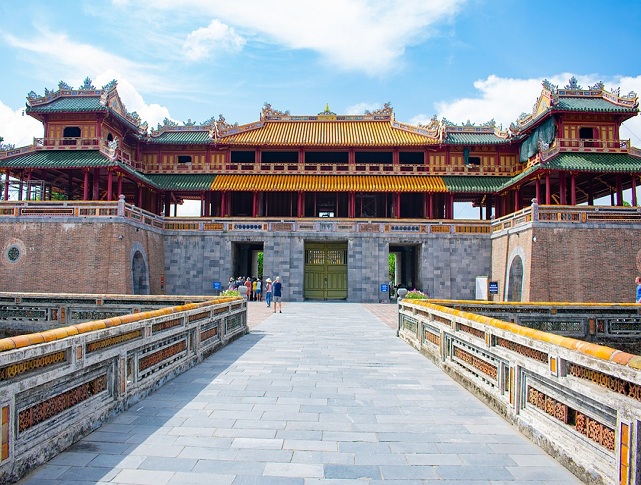 The Imperial City gate in Hue, Vietnam, featuring traditional royal architecture, stone bridges, and ancient walls under a clear blue sky.