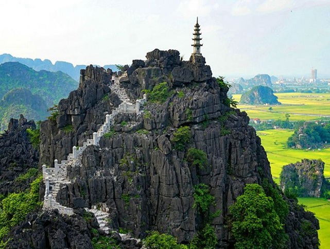 Stone staircase leading to the top of Mua Cave mountain in Ninh Binh with panoramic views of limestone peaks and rice fields.