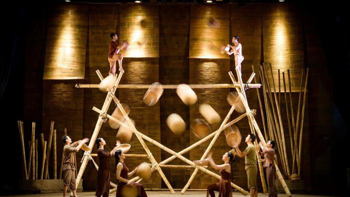 Performers balance on towering bamboo structures while juggling traditional bamboo trays during the Teh Dar Show, a contemporary Vietnamese bamboo circus featuring acrobatics, live music, and stunning stage design.