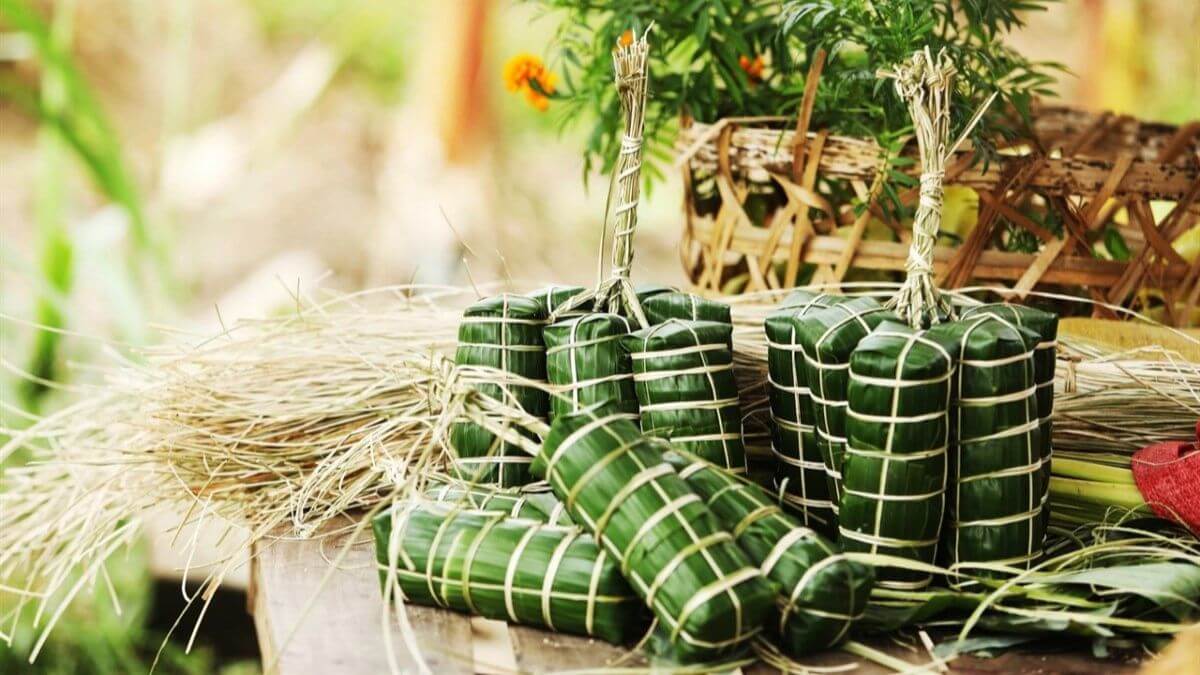 Traditional Vietnamese Bánh Chưng and Bánh Tét wrapped in green banana leaves, neatly tied with bamboo strings and displayed on a rustic table during the Lunar New Year season