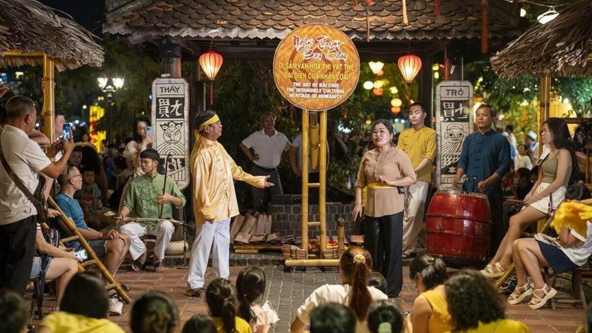 A traditional Vietnamese Bài Chòi performance takes place in an open-air courtyard at night, where performers sing and interact with the audience while visitors gather around to enjoy this UNESCO-recognized folk game and cultural art.