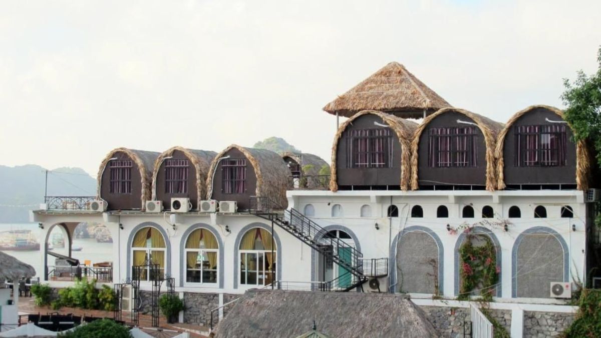 LePont Bungalow Hostel in Cat Ba features unique thatched-roof bungalow rooms overlooking the bay, with modern white architecture set against a scenic coastal backdrop.