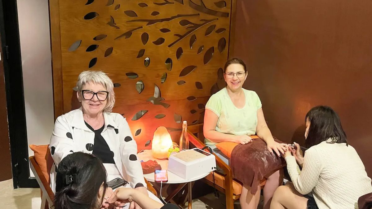Two travelers enjoying a relaxing foot spa and pedicure at a cozy wellness spa in Hanoi, with friendly staff providing professional nail care in a warm, inviting setting.