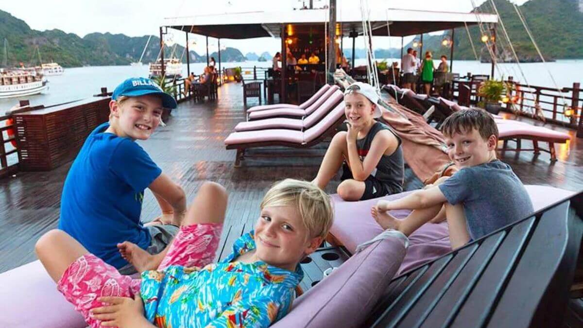 Foreign children relaxing on the sundeck of a cruise ship in Ha Long Bay, Vietnam, enjoying the scenic limestone islands and calm waters during a family holiday.