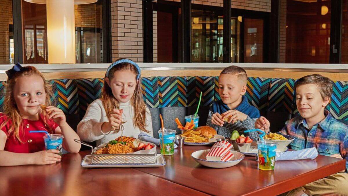 A variety of Western food for kids, including pizza, hamburgers, spaghetti, French fries, and fresh fruit served in a family-friendly restaurant.