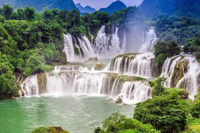 Majestic Ban Gioc Waterfall surrounded by lush green mountains and turquoise water in Cao Bang, Vietnam