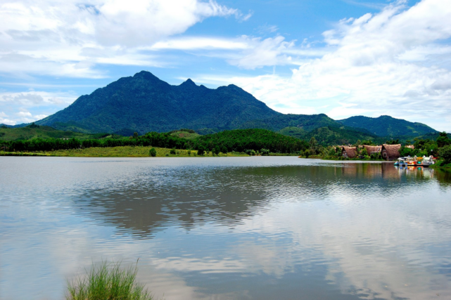 anoramic mountain and lake landscape with reflections under a bright blue sky in Ba Vi, Vietnam.