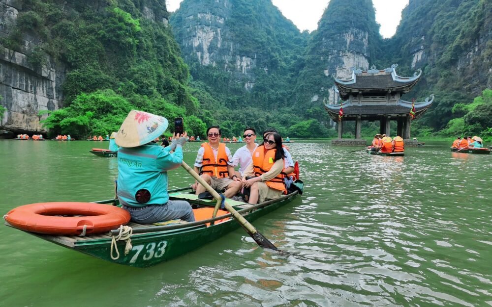 Traditional boat ride through the scenic waterways and limestone mountains of Trang An in Ninh Binh, Vietnam.