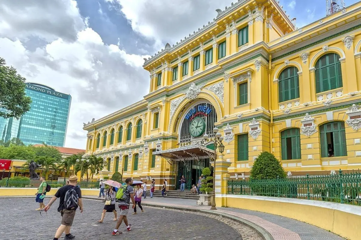 Saigon Central Post Office in Ho Chi Minh City featuring French colonial architecture and tourists walking outside.