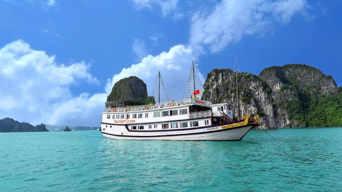 Sunlight Cruise sailing through the emerald waters of Ha Long Bay, surrounded by dramatic limestone islands and stunning natural scenery.