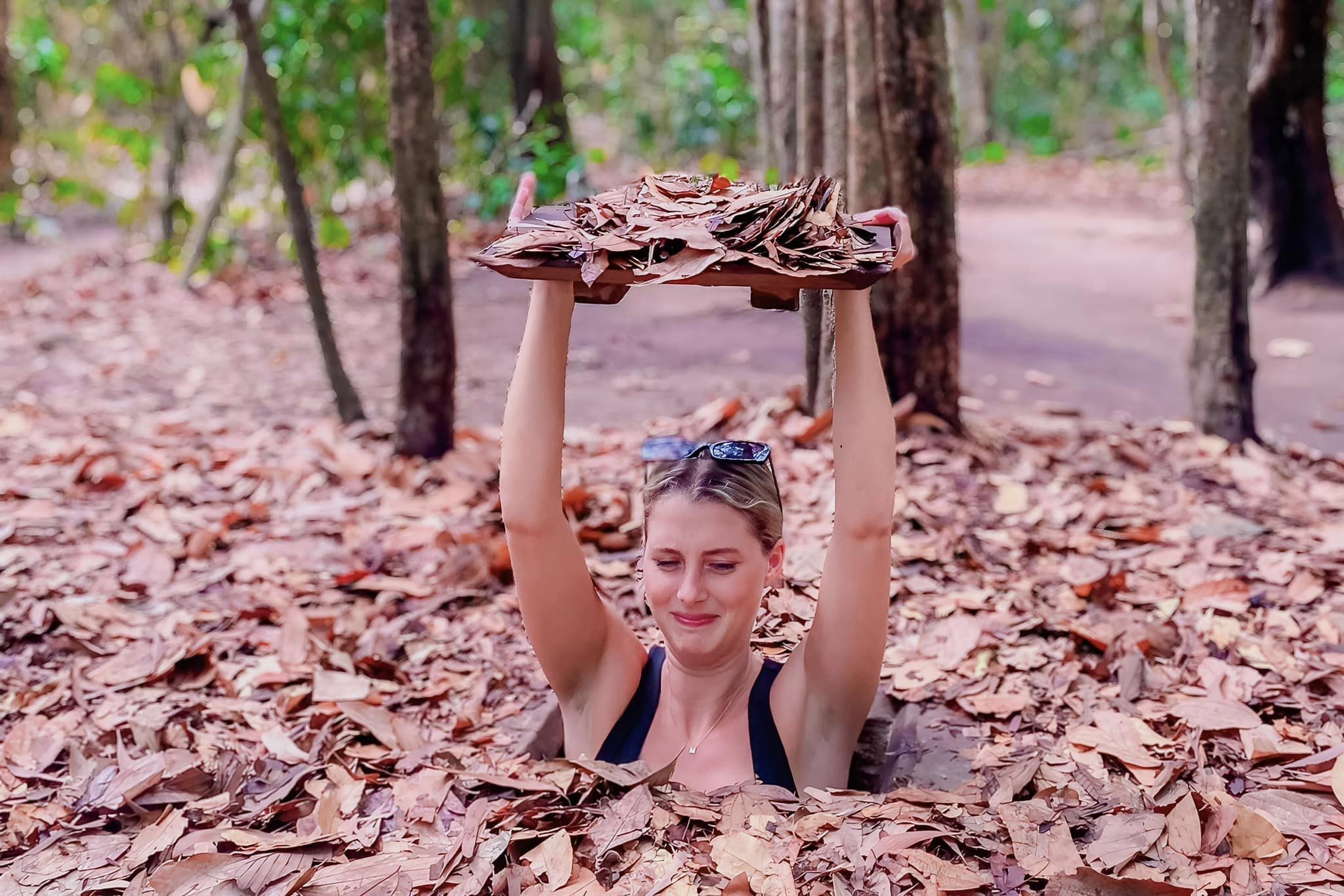 Foreign tourist experiencing a hidden camouflage trapdoor at Cu Chi Tunnels