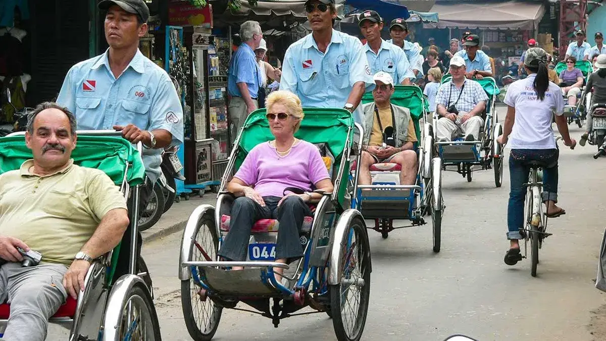 Cyclo drivers waiting for tourists on a busy street in Hanoi, highlighting the importance of agreeing on prices before taking a cyclo ride in Vietnam.