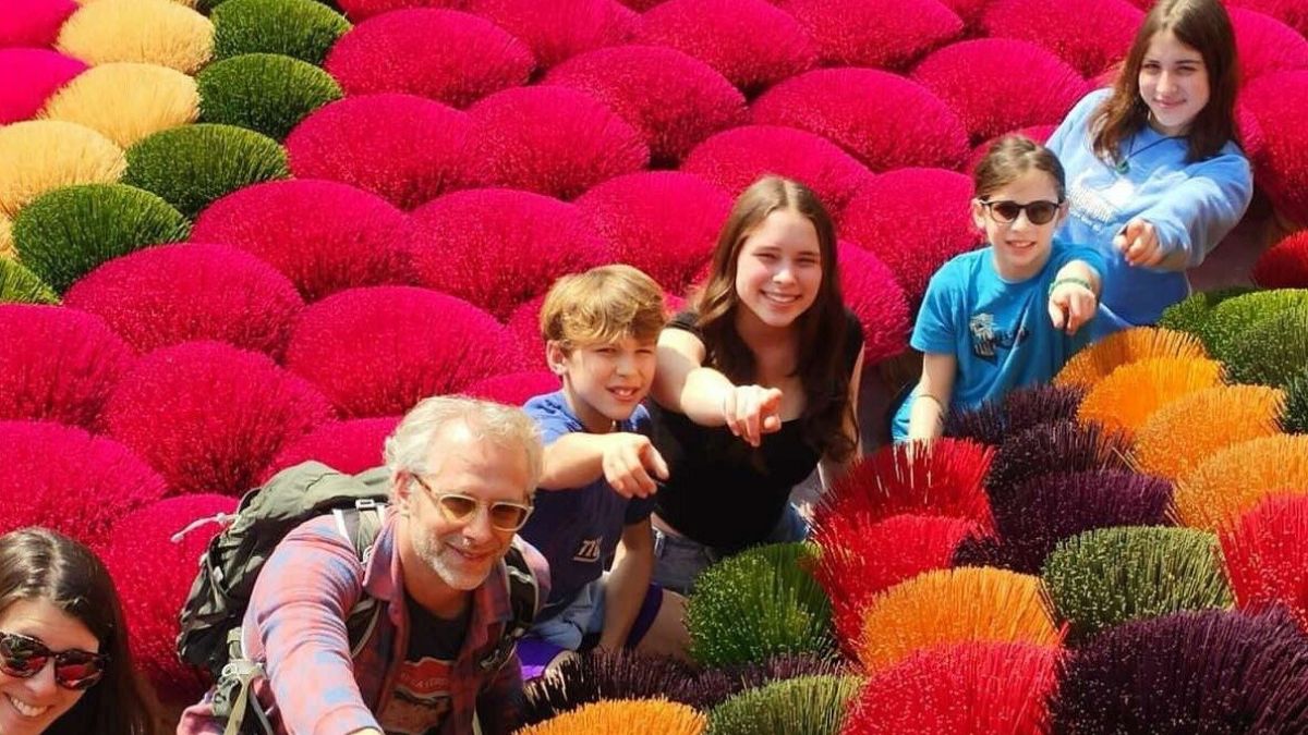 Family taking photo among colorful red incense sticks drying in the sun at Quang Phu Cau Incense Village near Hanoi, Vietnam.