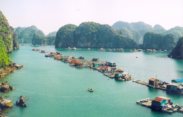 Floating fishing village surrounded by limestone islands and emerald waters in Lan Ha Bay, Vietnam.