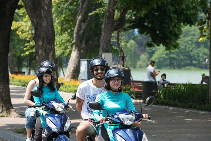 Local drivers riding tourists on motorbikes through the busy streets and hidden alleys of Hanoi, Vietnam.
