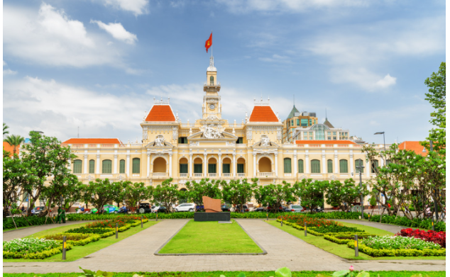 Ho Chi Minh City Hall building with Vietnamese flags, gardens, and colonial-style architecture in Ho Chi Minh City, Vietnam