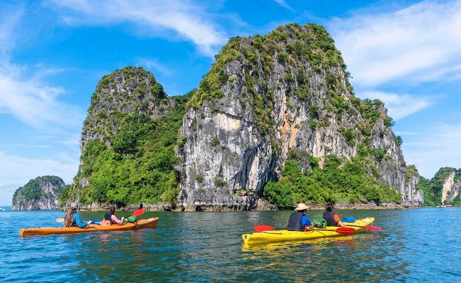 Travelers kayaking through the limestone islands and clear waters of Ha Long Bay, Vietnam.