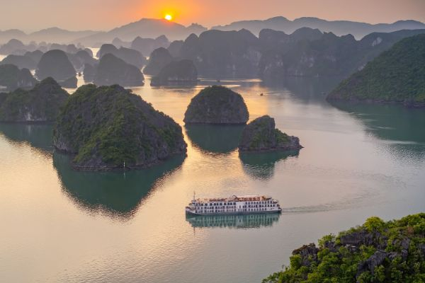 Sunset view over Lan Ha Bay with a cruise sailing among limestone islands in northern Vietnam.