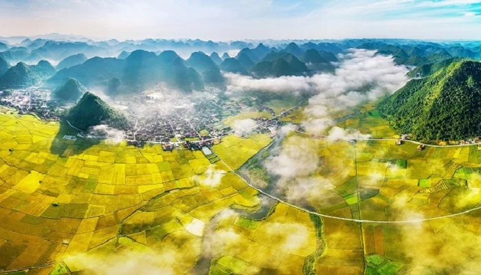 Aerial view of Lang Son with golden rice fields, misty clouds, and limestone mountains in northern Vietnam.