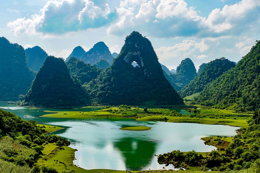 Panoramic view of emerald lakes and dramatic limestone mountains in Cao Bang, Vietnam.