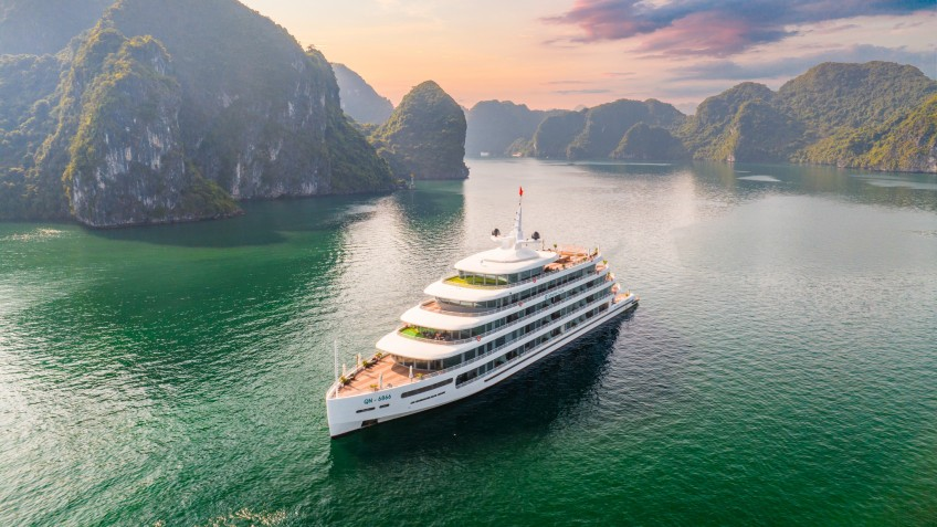 Luxury cruise sailing through the emerald waters and limestone islands of Ha Long Bay, Vietnam.
