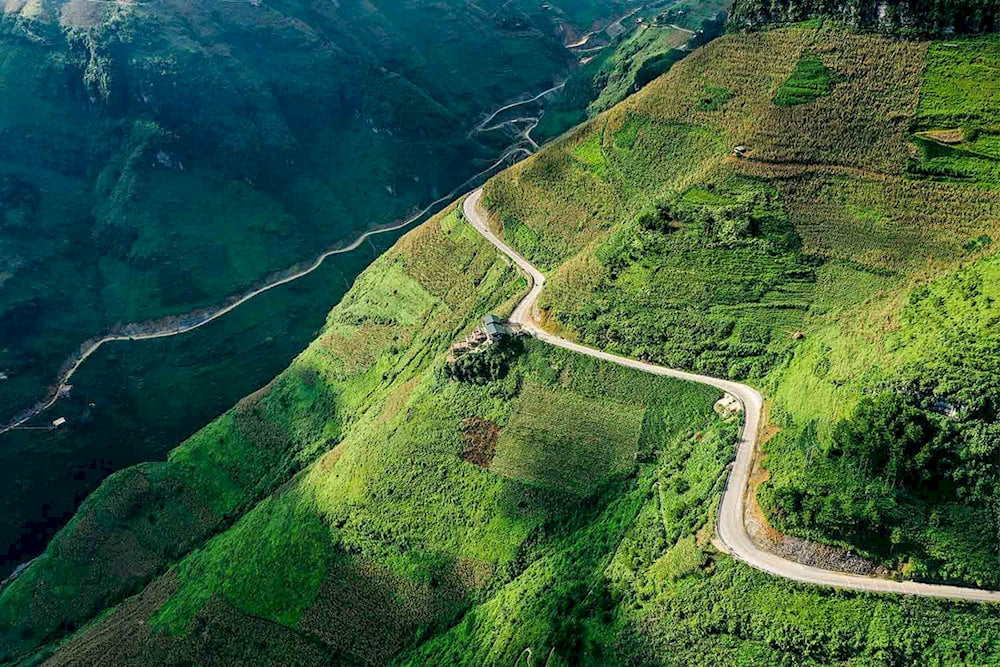 The winding Ma Pi Leng Pass road cutting through the lush green mountains of Ha Giang, Vietnam