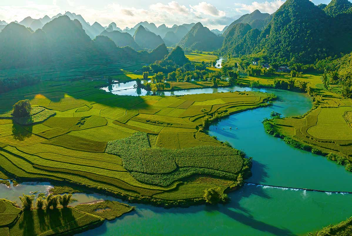 Aerial view of Phong Nam Valley with winding turquoise rivers, rice fields, and limestone mountains in Cao Bằng, Vietnam