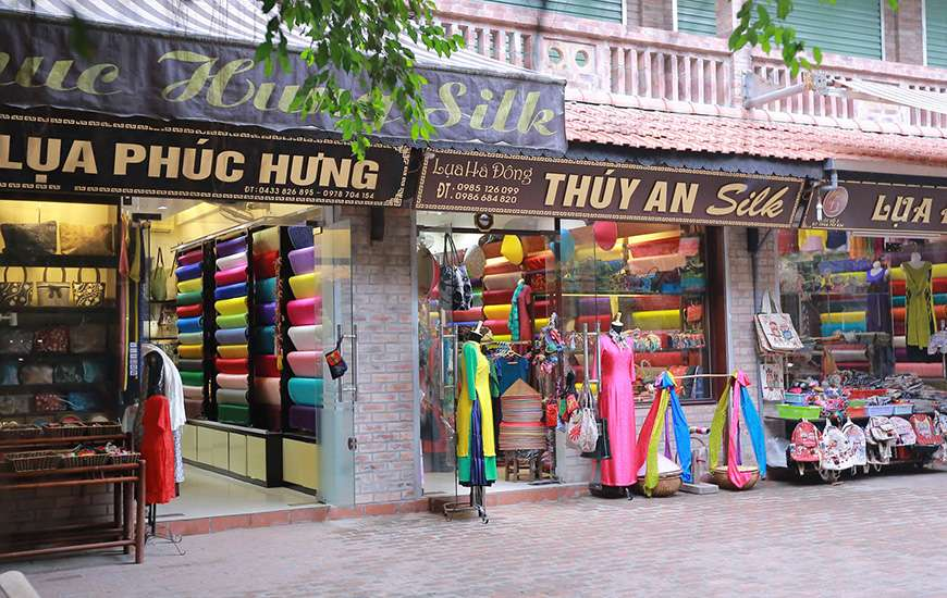 Colorful silk shops in Vietnam displaying traditional fabrics, scarves, and handmade souvenirs along a local shopping street.