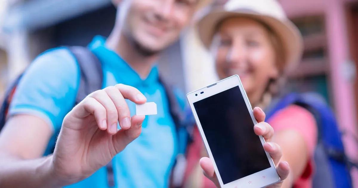 Tourists holding a smartphone and SIM card while traveling in Vietnam, illustrating common SIM card scams targeting international visitors