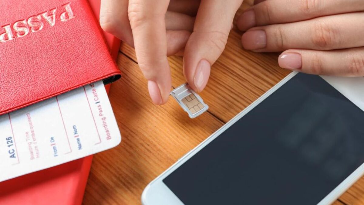 Traveler holding a SIM card next to a smartphone and passport, illustrating the importance of choosing reliable mobile services while traveling in Vietnam.