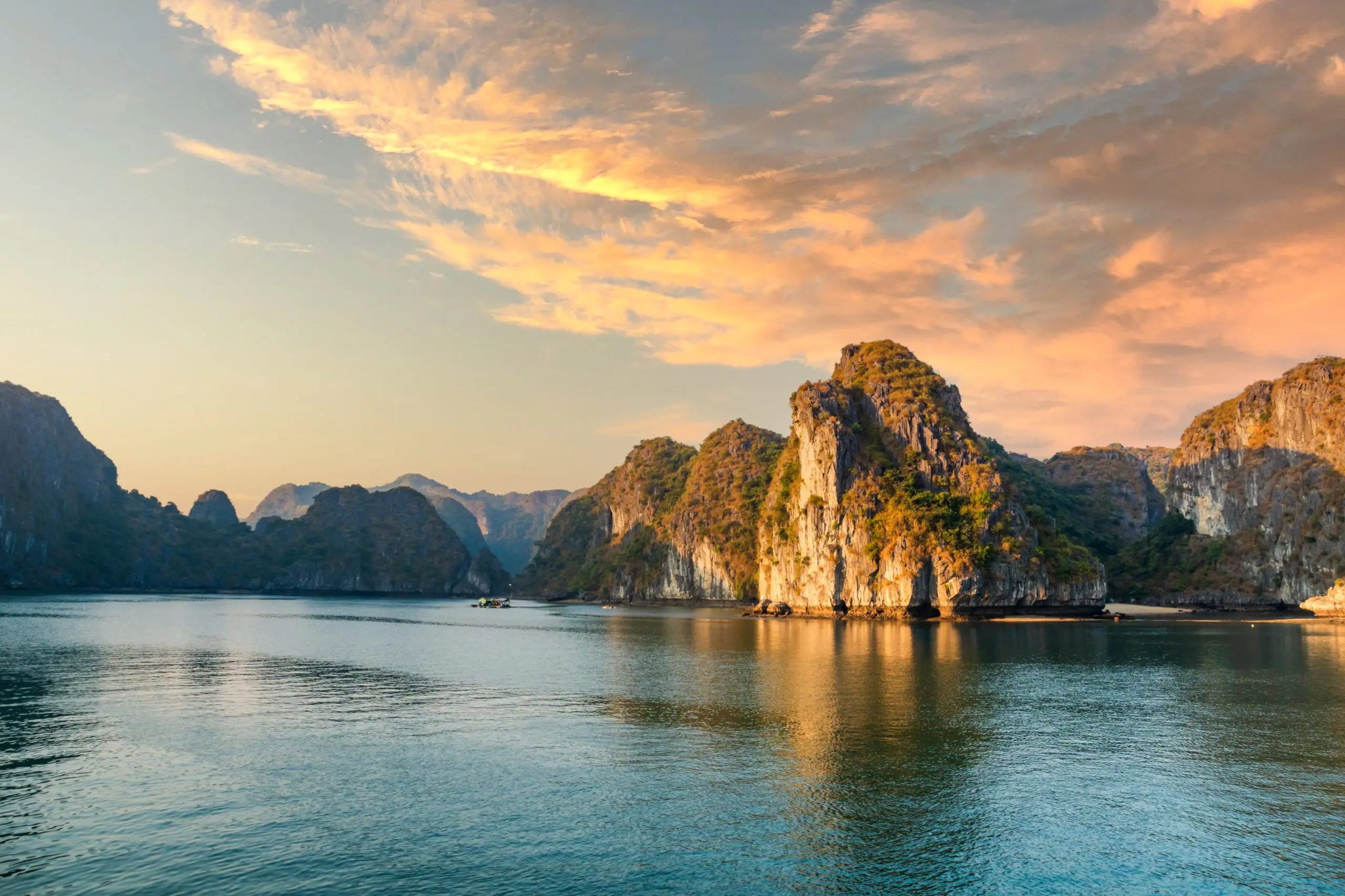Sunset over the limestone islands and calm emerald waters of Ha Long Bay, Vietnam