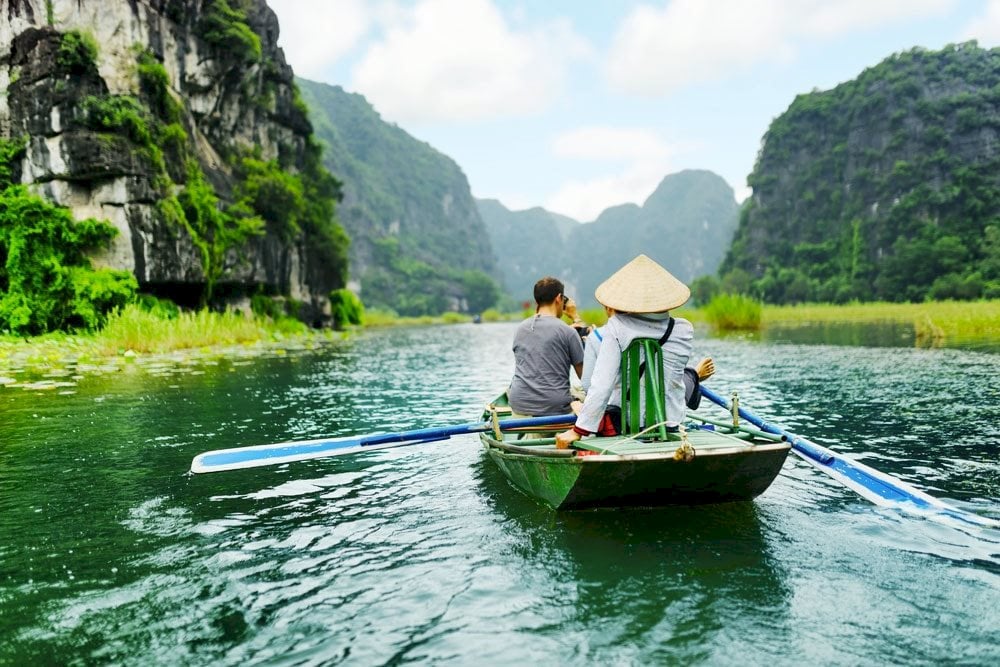 Visitors taking a boat ride through the limestone landscape of Tam Coc in Ninh Binh, Vietnam.