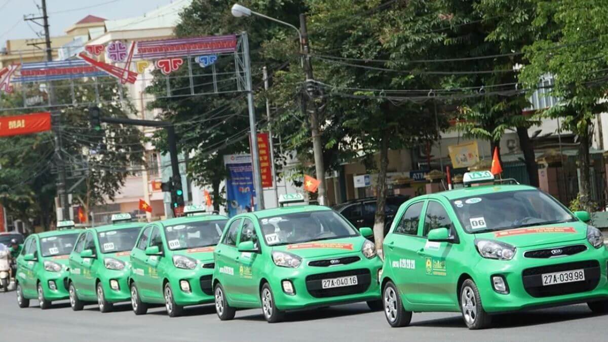Green Mai Linh taxi operating on a city street in Vietnam, a popular transportation option for tourists and local travelers.
