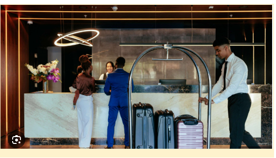 Hotel guests checking in while a hotel staff member assists with luggage in a modern lobby