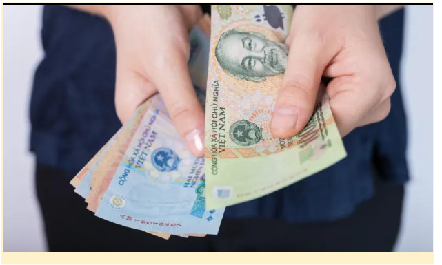Person holding Vietnamese Dong banknotes for cash payment or tipping in Vietnam