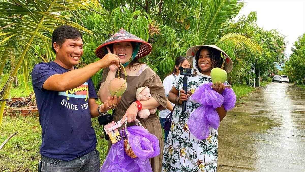 International tourists picking fresh mangoes at a fruit garden in the Mekong Delta, Vietnam, with local residents.