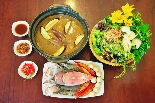 Traditional Mekong Delta hotpot served with seafood, fresh vegetables, herbs, and noodles