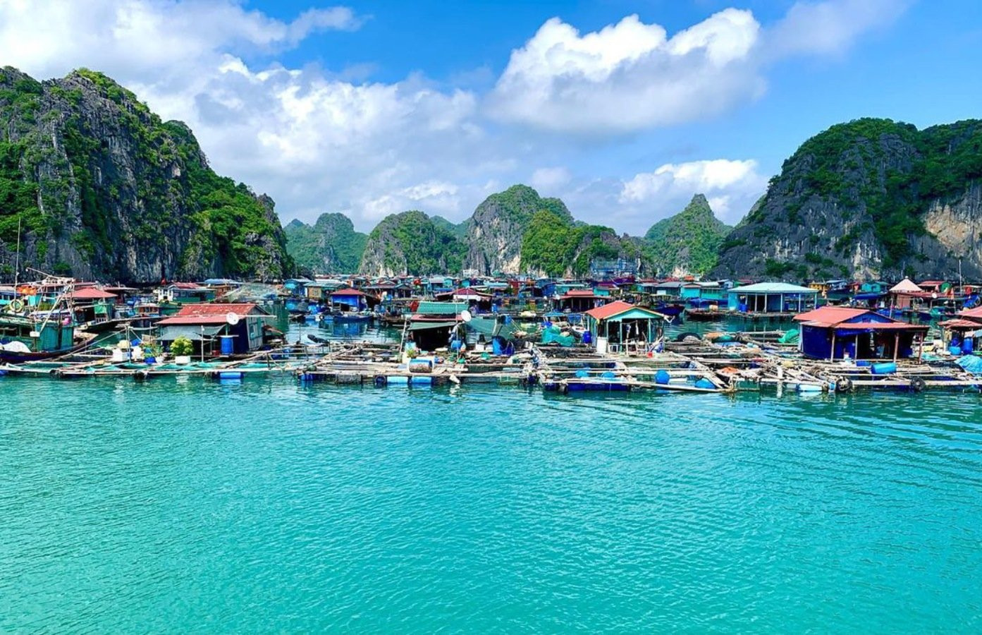 Floating fishing village surrounded by limestone islands and emerald waters in Ha Long Bay, Vietnam.