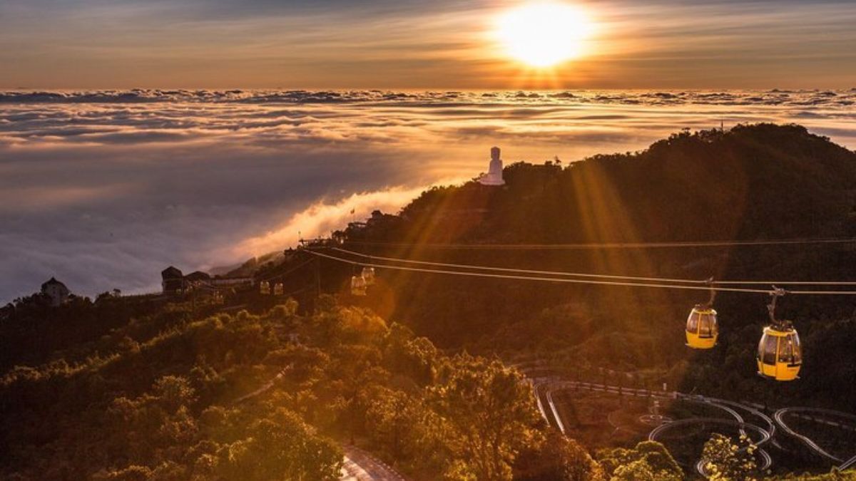 Ba Na Hills cable car at sunrise above a sea of clouds in Da Nang, Vietnam, with panoramic mountain views and the Linh Ung Buddha statue.