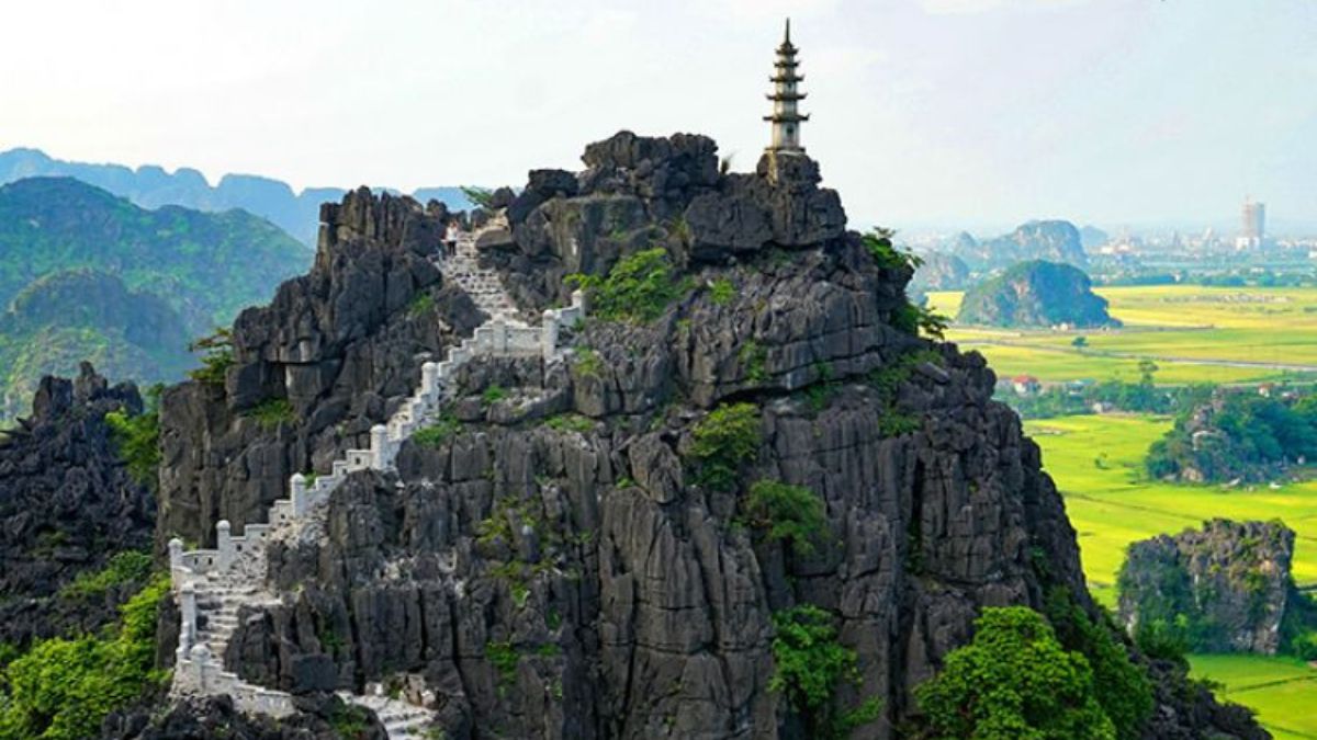 The iconic stone staircase leading to the summit pagoda at Mua Cave, surrounded by towering limestone cliffs and panoramic views of Tam Coc in Ninh Binh, Vietnam.