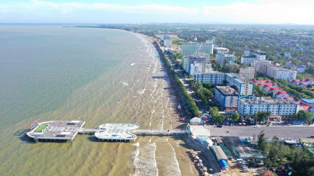 Peaceful coastline at Hai Tien Beach in Thanh Hoa with soft sand, gentle waves, and a scenic wooden pier.
