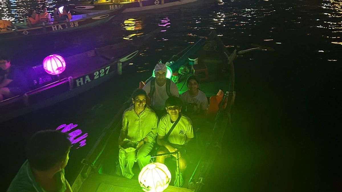 A family enjoys a traditional lantern boat ride on the Hoai River in Hoi An at night, surrounded by colorful lantern-lit boats and the lively riverside.