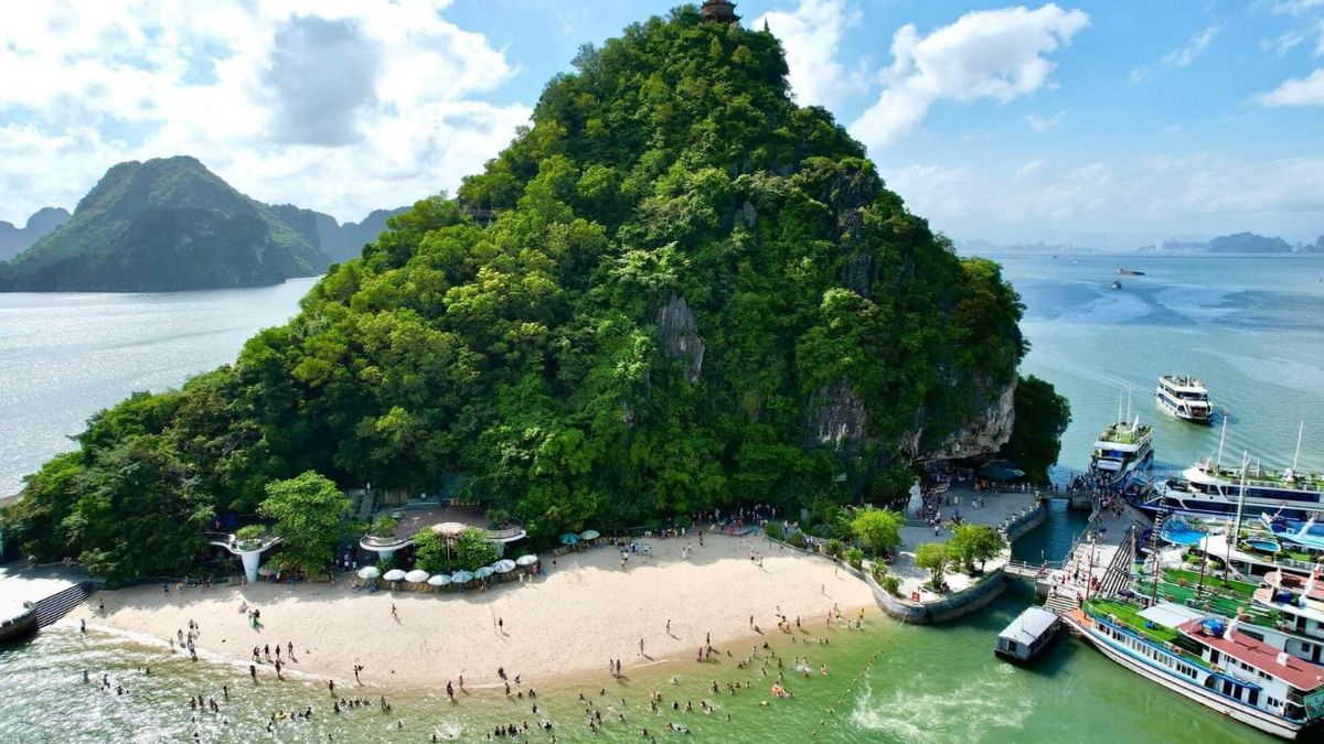 Panoramic view from Titop Island overlooking Ha Long Bay with emerald water, limestone karsts, and a crescent-shaped beach.