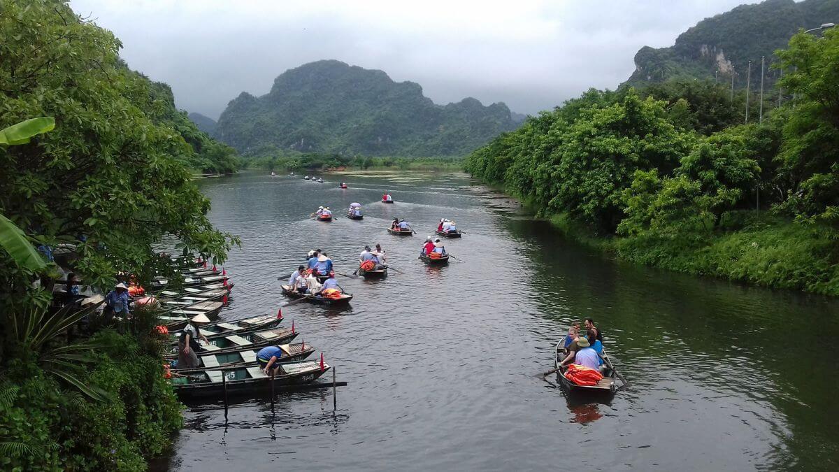 Tourists enjoying a traditional bamboo boat ride through the peaceful waterways of Van Long Nature Reserve in Ninh Binh, Vietnam.